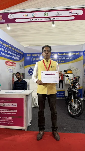 Ola Car Wash representative holding certificate at exhibition booth Kanpur 2026